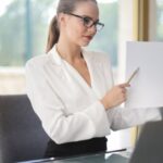 Wellness Plan - Determine female executive manager in formal wear sitting at table with laptop in office and explaining business plan