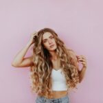 Balayage - woman standing next to pink wall while scratching her head