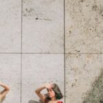 Sun Protection - Photo of Two Women Standing by Wall Posing While Blocking Sun with Their Hands