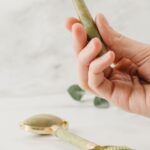 Jade Roller - Person Holding Silver Spoon With White Flower Petals