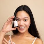 Hyperpigmentation - woman in white tank top holding white labeled bottle