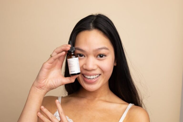 Hyperpigmentation - woman in white tank top holding white labeled bottle