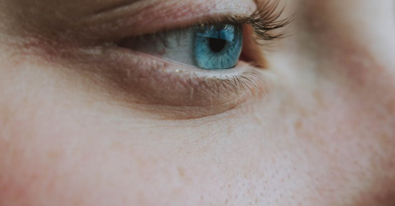 Eyebrow Shaping - Closeup side view of crop anonymous wistful female looking away with turquoise eye and black eyelashes with brown eyebrows and pores on face skin