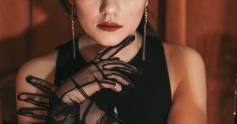 Makeup Lasting - A woman in black gloves and a long dress sitting at a table with candles