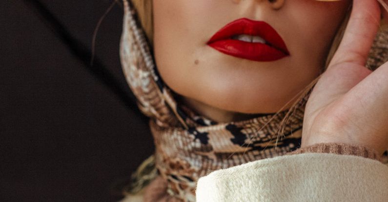 Makeup Shades - Low angle of gorgeous young lady with red lips in elegant outfit adjusting trendy sunglasses while standing on street with umbrella